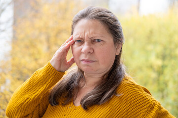 mature woman suffering from severe migraine, holding head in pain, pained expression, migraine...
