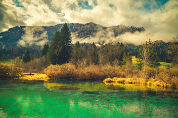 A tranquil scene from Kranjska Gora, Slovenia, featuring a crystal-clear turquoise lake in the foreground.