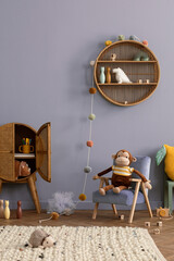 Cozy composition of kid room interior with round shelf, gray desk, green armchair, blue wall, braided rug, plush toys, braided basket, block toys and personal accessories. Home decor. Template.