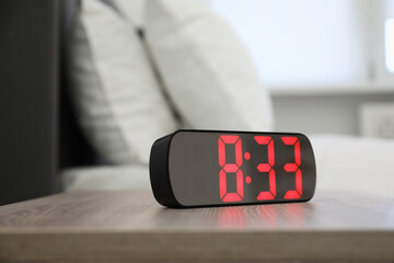 Digital alarm clock showing 8:33 o'clock on bedside table indoors