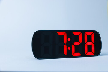 Digital alarm clock showing 7:28 o'clock on grey background