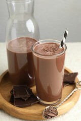Tasty chocolate milk with shavings and pieces on white table