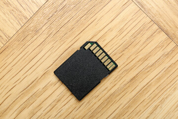 One SD memory card on light wooden table, top view