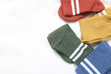 Different soft socks on white blanket, top view. Space for text