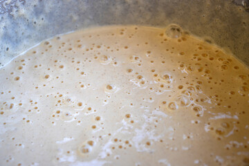 Closeup, top view of smooth texture of cake batter with bubbles in in a metal mixing bowl. Pie or pancake dough background

