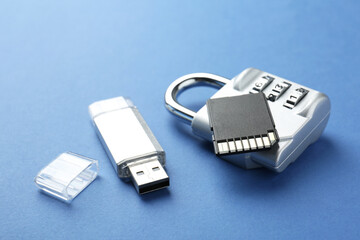 Flash drive, SD memory card and combination padlock on blue background, closeup