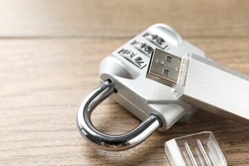 Flash drive and combination padlock on wooden background, closeup. Space for text