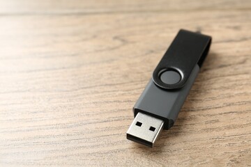 One flash drive on wooden background, closeup. Space for text