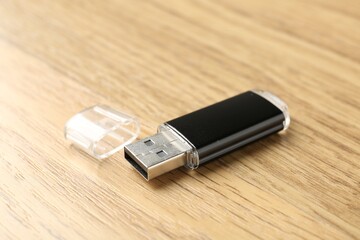 One flash drive on wooden background, closeup. Space for text