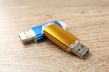 Two flash drives on wooden background, closeup