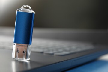 Flash drive and laptop on table, closeup. Space for text