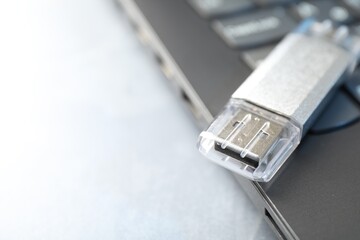 Flash drive and laptop on gray table, closeup. Space for text