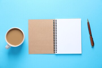 Open blank notebook, pen and coffee on light blue background, flat lay