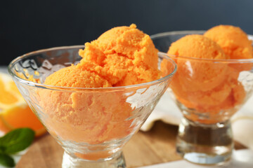 Balls of tasty orange sorbet in dessert bowls on table, closeup
