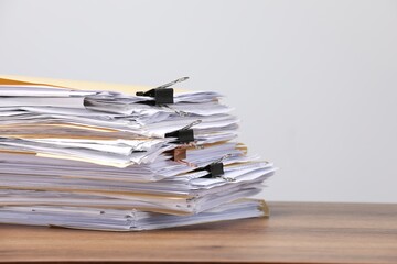 File folders with papers and binder clips on wooden table against gray background, closeup. Space for text