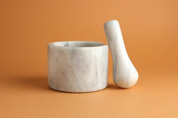 Marble mortar and pestle on light brown background, closeup
