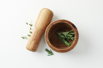 Wooden mortar with rosemary, thyme and pestle on white table, flat lay