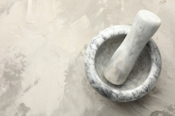 Marble mortar and pestle on grey textured table, top view. Space for text