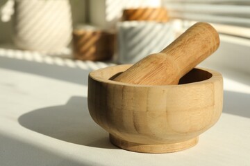 Wooden mortar and pestle on windowsill indoors, closeup