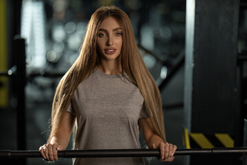 determined woman holds barbell in gym setting dressed in casual athletic wear. atmosphere is...