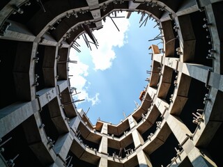Obraz premium A view looking up through the center of a circular building under construction, revealing the sky through the unfinished structure.