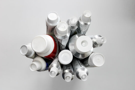 Close-up of cream and ointment tubes with unrecognizable print isolated on a white background. Dermatology healthcare design element with bokeh light effect. Top of caps foreground focus.