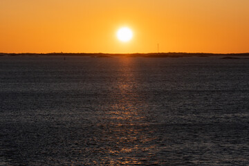 Captivating sunset over the boundless expanses of the sea, where the sun kisses the horizon, painting the sky in fiery colors and leaving a golden path on the water.