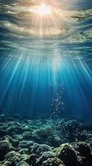 Obraz premium Underwater sunlight beams through water with bubbles and coral reefs, surface reflections.