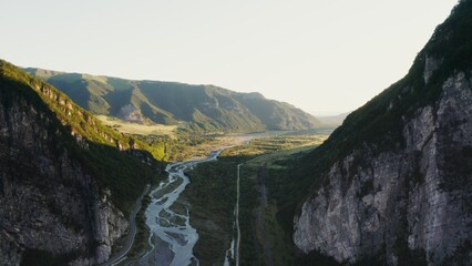Panoramic shooting from a quadcopter. View of a mountain valley bathed in sunlight. Green hills...