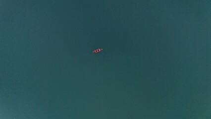 A young guy and a girl are sailing on a rowing boat on the lake. A couple on a canoe take a photo in the middle of a pond. Top view from a quadcopter
