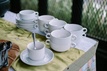 Neatly Stacked White Coffee Cups and Saucers on a Buffet Table