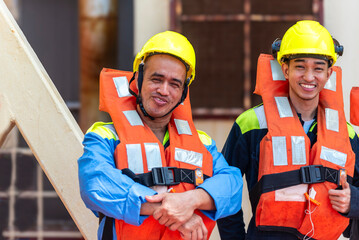 Crew members wear life jackets as they gather for an abandon ship drill, reviewing lifeboat...