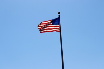 The American flag against the blue sky background.