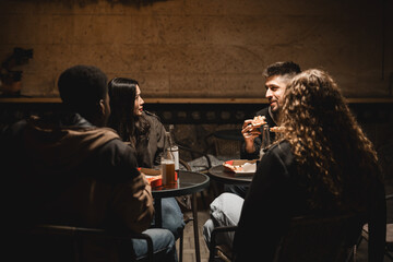 Friends enjoy a casual meal in a cozy setting at night in an urban area