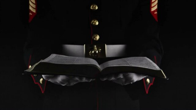 Marine holding open Bible in dress uniform 