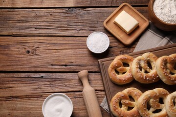 Tasty pretzels and ingredients on wooden table, flat lay. Space for text