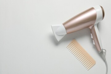 Hair dryer and comb on white background, top view. Space for text