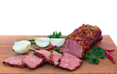 Smoked beef with pieces and spice, red chilli pepper, bulb onion and green leaves onion and parsley on wooden cutting board on a white background with space for text. Top view, flat lay
