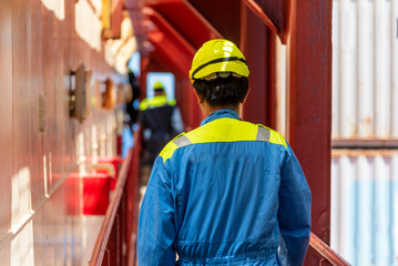 Deck officer seen from behind walking between containers and superstructure during an abandon-ship...