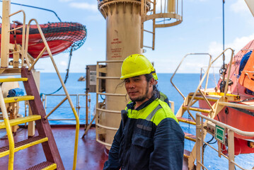 Portrait of a young Filipino marine engineer aboard a large container ship, gazing ahead with a thoughtful yet content expression - carrying both pride and longing across distant seas. Real workplace.