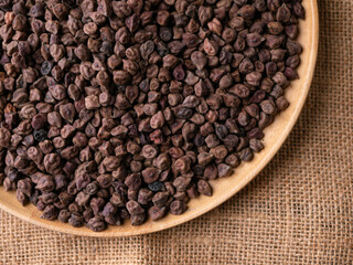 Raw Dark Brown Chickpeas (Kala Chana) on a rustic wooden table. Dry Balck chickpea (ceci neri) background close up.