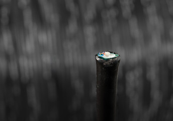 Fiber optic cable in front of defocused black cable reel. Close up of loose tube cable. Install or...