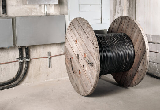 Fiber optic wooden cable reel in electrical room. Large 1000m loose tube cable wood drum. High-speed internet upgrade or installation of fiber optic to building in progress. Selective focus.