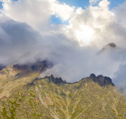 mountain ridge in dense mist and clouds under a sparkle sun