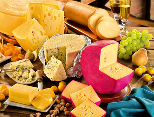 mesa com queijos variados, frutas e taça de vinho
