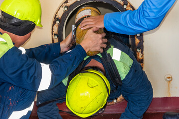 Crew member wearing breathing apparatus exits a narrow hatch after providing first aid during a man...