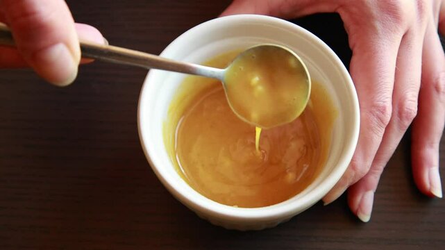 Close-up video of mixing mustard, honey, and garlic in a small bowl. Perfect for salad dressing, marinade, or dipping sauce content.