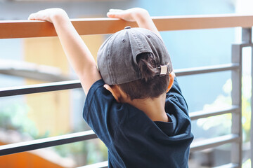 rear view, boy hanging from balcony railing
