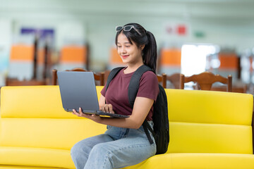 In the university library, an Asian female student types on her laptop, eagerly pursuing education...