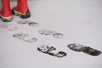 Trail of muddy footprints of boots on the carpet. Concept of housecleaning and dirt stains.The cozy...